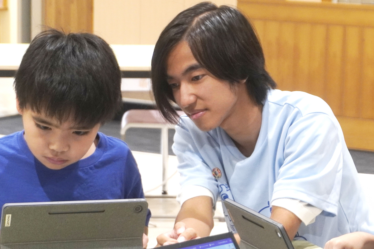 現地スタッフとこどもが一緒にプログラミングをしている