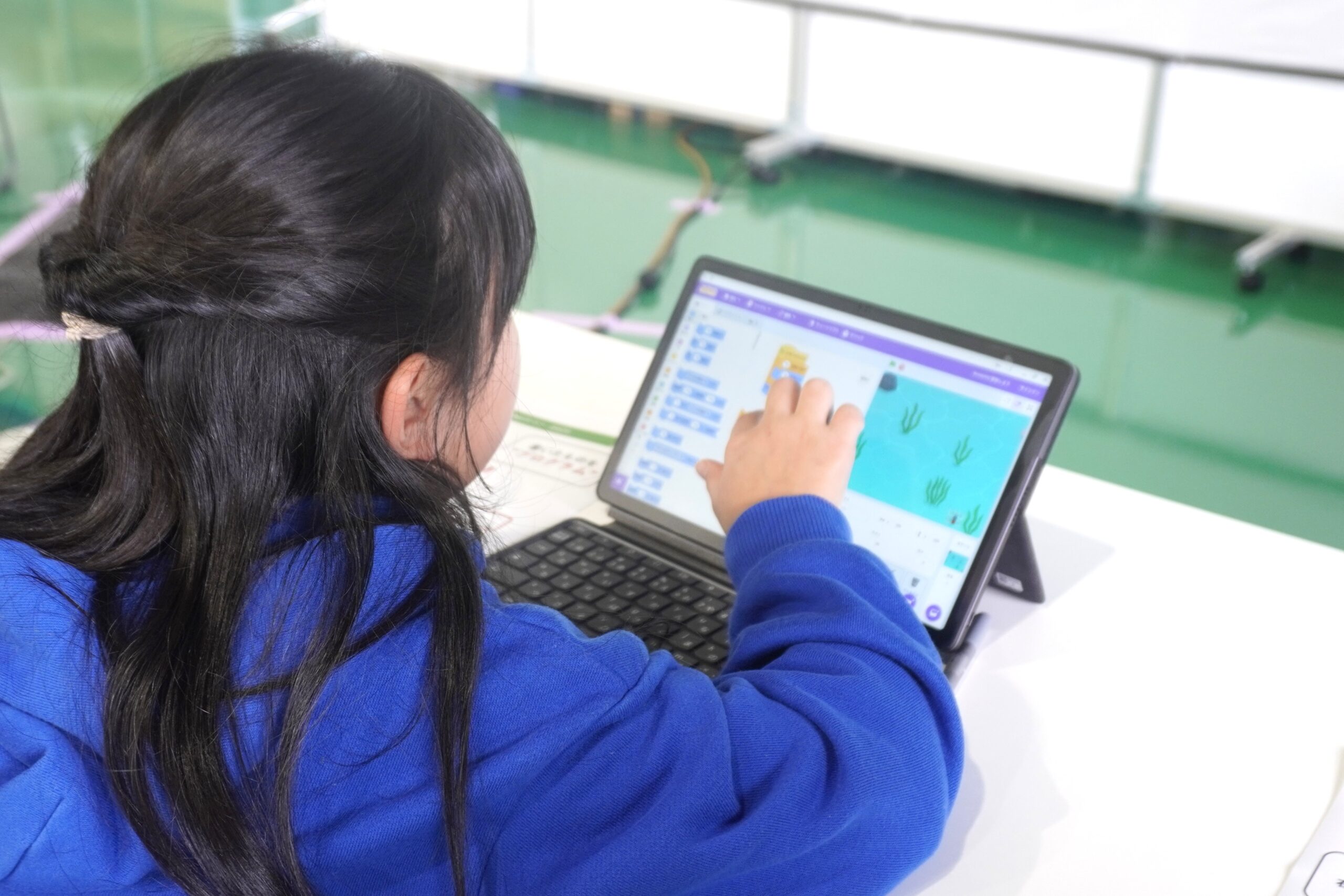 タッチ操作をしている子どもの後ろ姿